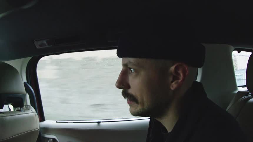 A man rides in the back of a car