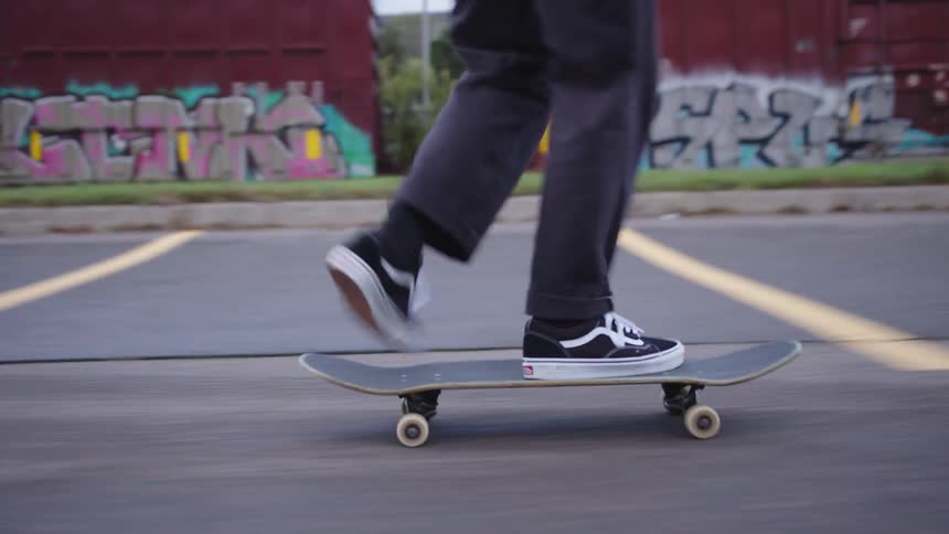 The man crouches while riding his skateboard