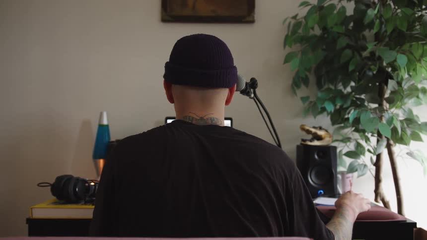 Person sitting facing a desk with a microphone and laptop