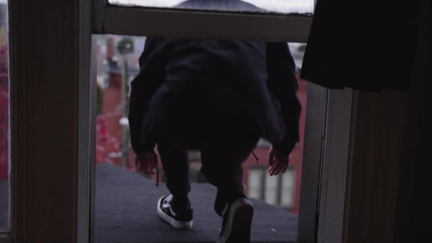 The man steps out the window and sits on the roof