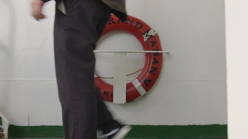 Red lifebuoy mounted on white wall with green bottom trim accompanied by orange signaling device