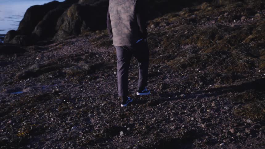 The man is walking past the coastline