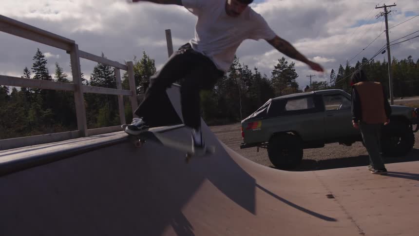 Man skateboarding down a wooden ramp in an outdoor skatepark