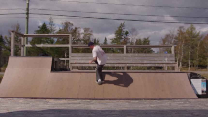 Young man skateboarding on an outdoor wooden ramp