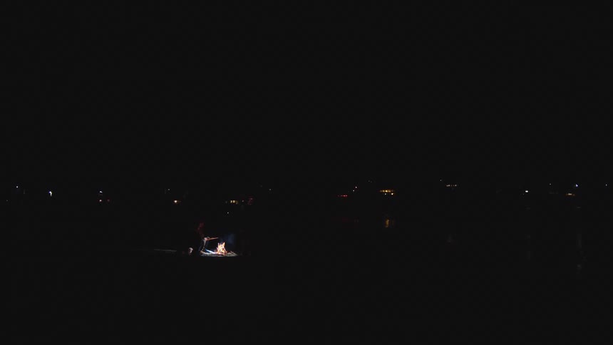 People are sitting and standing around the campfire