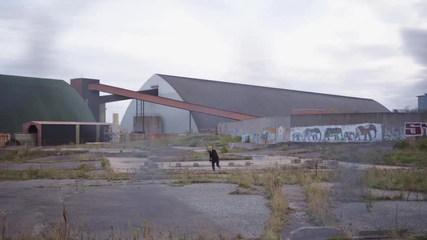 A person skateboards in an empty lot