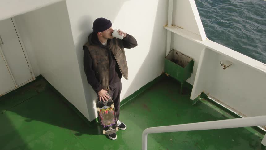 A man holding a skateboard on a boat