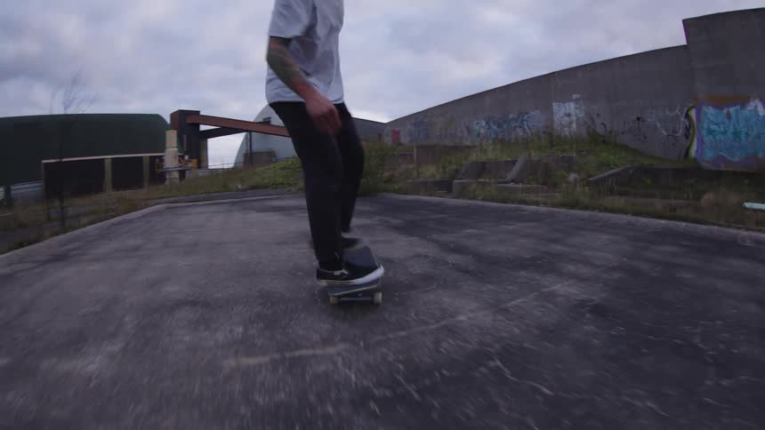 Skateboarder performs a jump in an urban area surrounded by graffiticovered walls