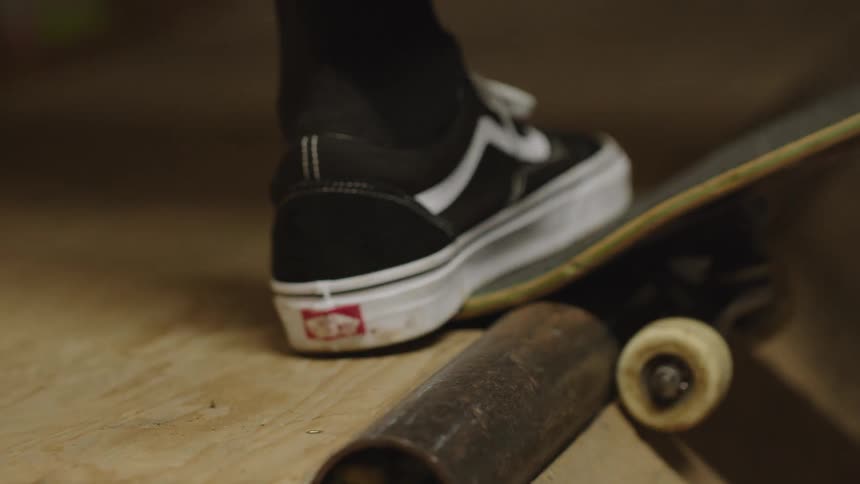 A person is at the top of a skateboard ramp and then rides down