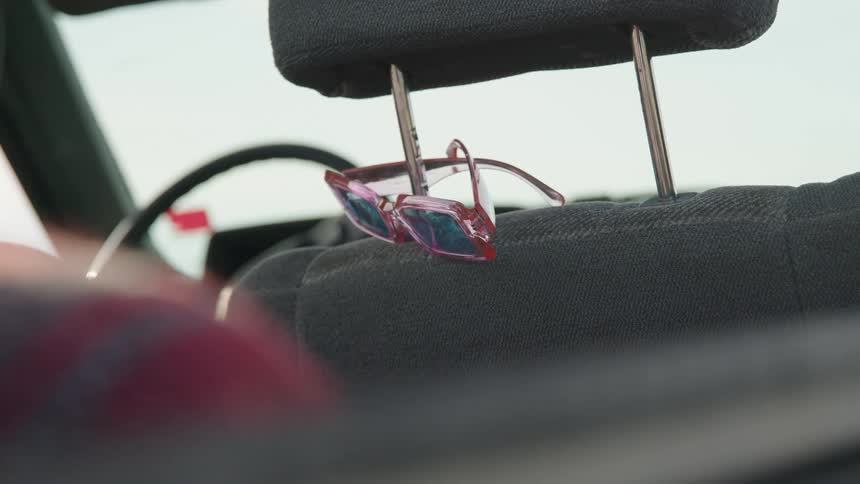 Sunglasses hang from the car headrest