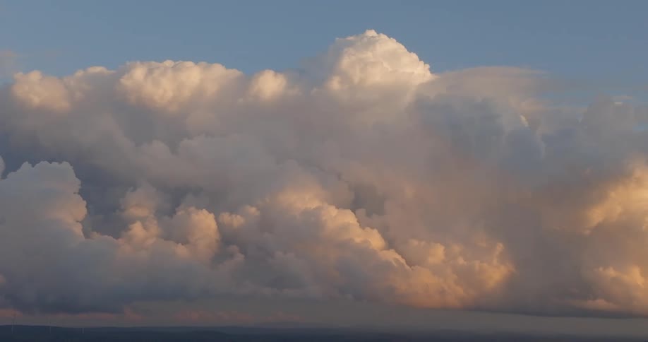 White clouds blanket the sky as the golden sun casts a warm radiant glow across their surface creating a soft luminous shimmer that brightens the midday atmosphere