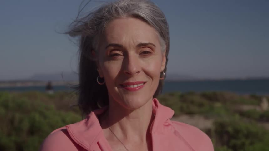The woman is smiling as the wind blows her hair
