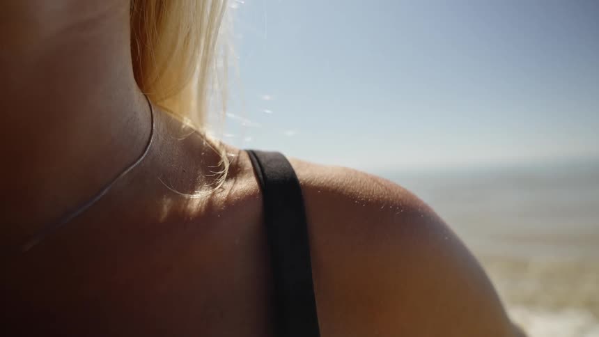The bright sun shines on the woman by the water