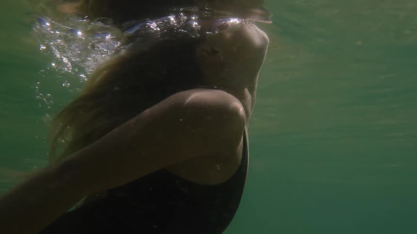 Swimmer moves underwater in a black suit