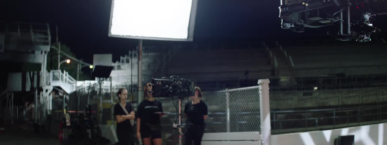 Singer performs on an outdoor stage at night while being filmed up close