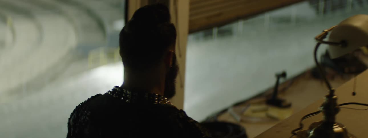 Man looking out the window of a studio lit by artificial night light