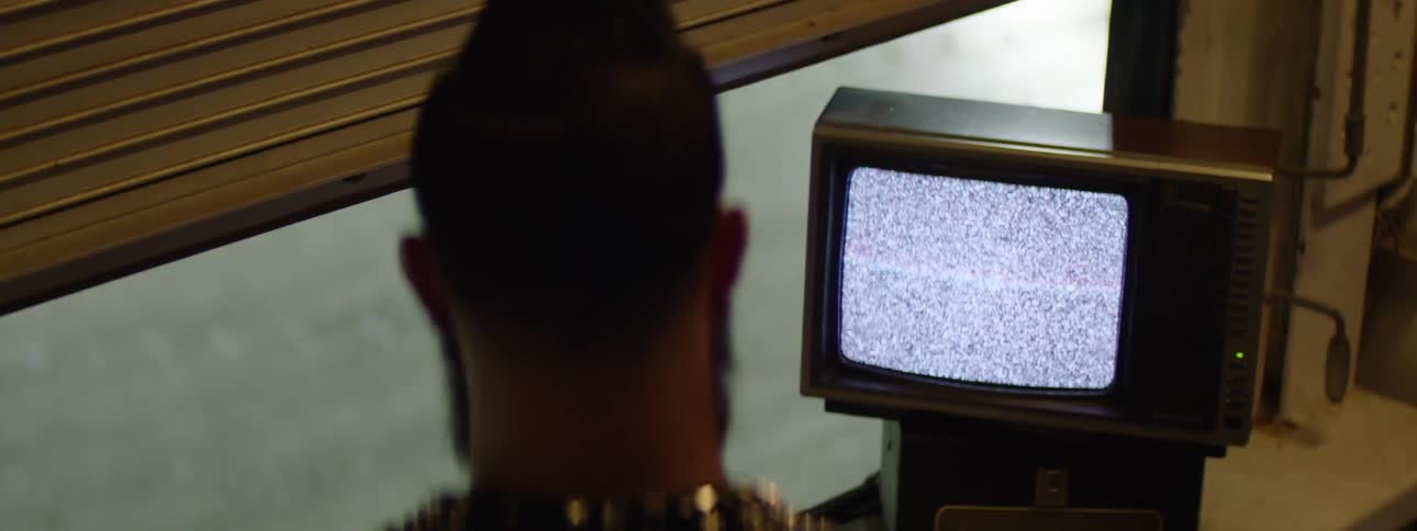 Man watches an old television displaying static in a dimly lit room