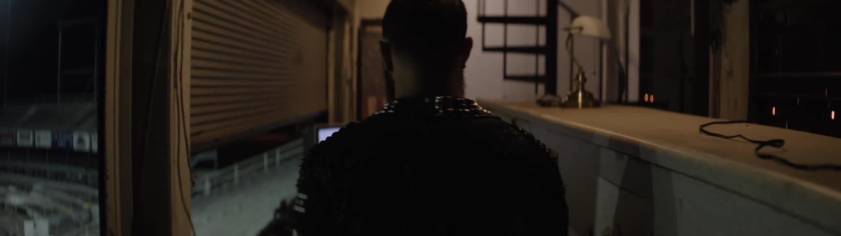 Man in a dark jacket walking inside a booth facing illuminated stands