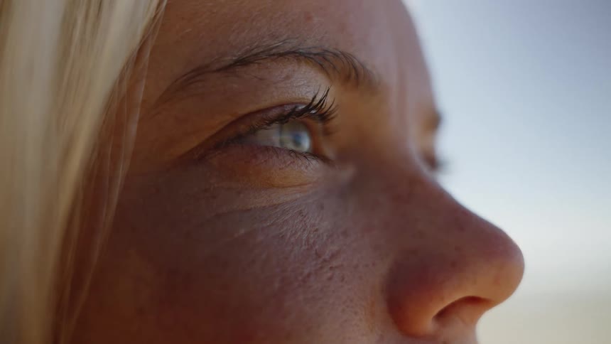 A womans freckled face in close profile gazes toward the bright sky