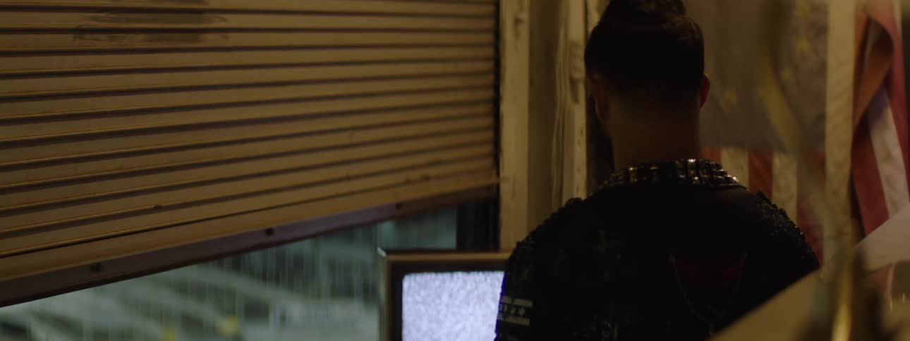 Man watches static screen in industrial setting with american flag and partially open metal door