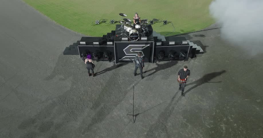 A musical band plays outdoors on a grassfield at midday