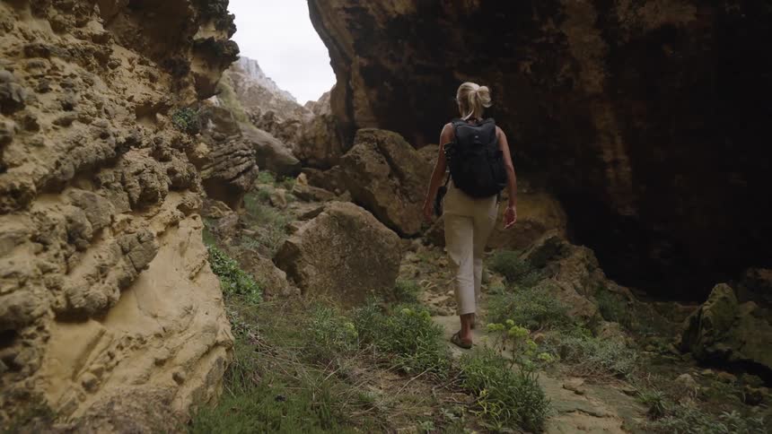 Woman walking among rocks on a trail surrounded by rock formations