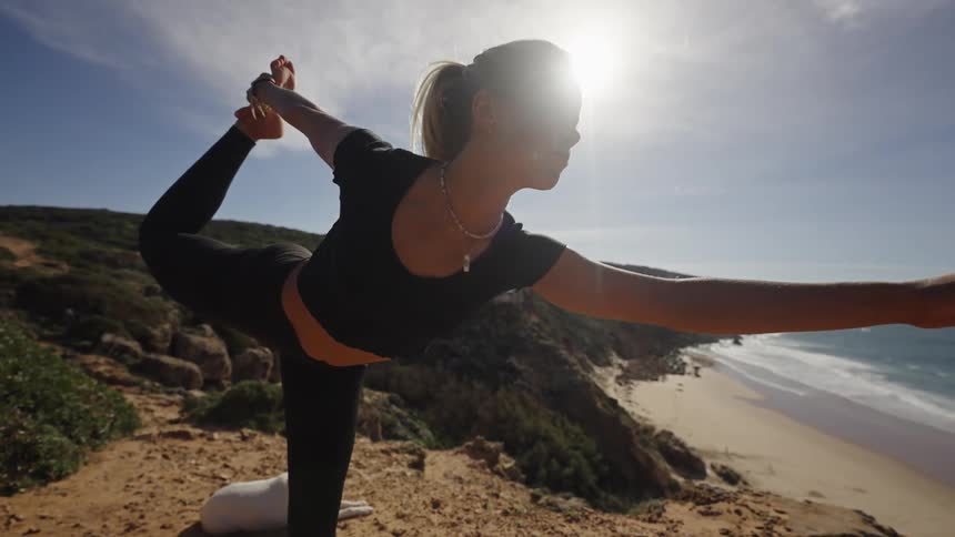 Woman practicing yoga in balance facing the sea