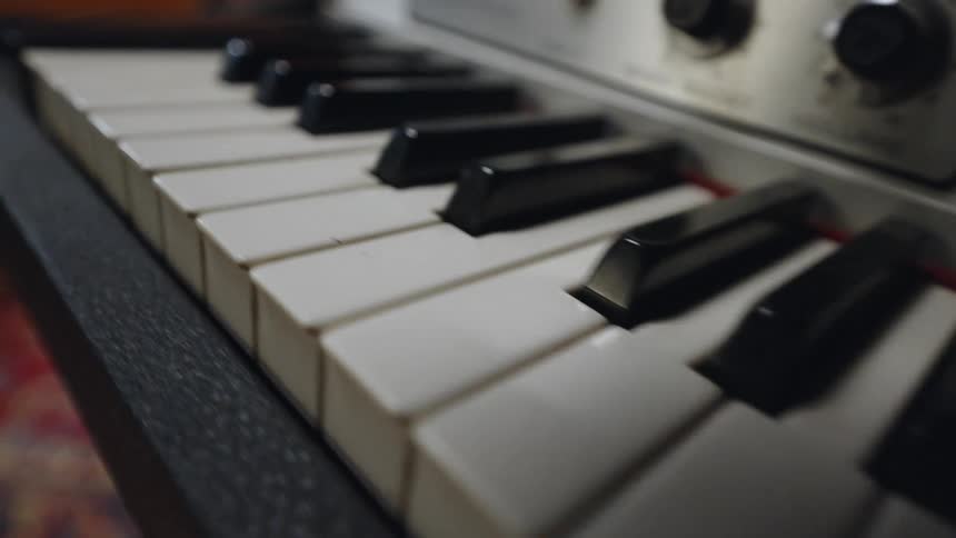 A closeup shot shows the white and black keys of a musical keyboard or piano the rows of keys extend from the bottom to the top of the frame and its on an indoor setting