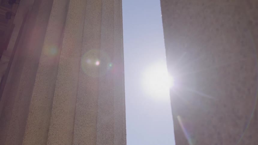 Sunbeam shining between stone columns under a clear sky