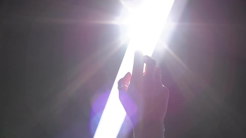 Person's hand reaching up toward a light