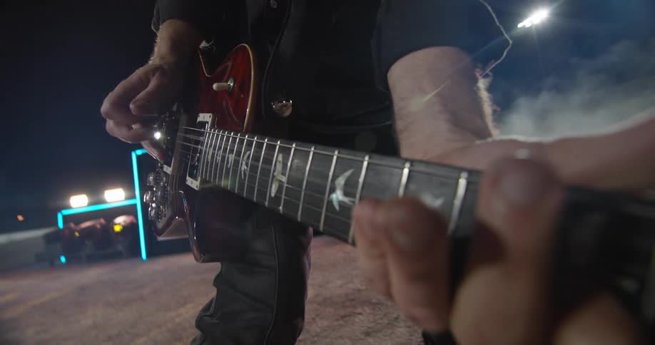 Musician plays an electric guitar during a nighttime performance