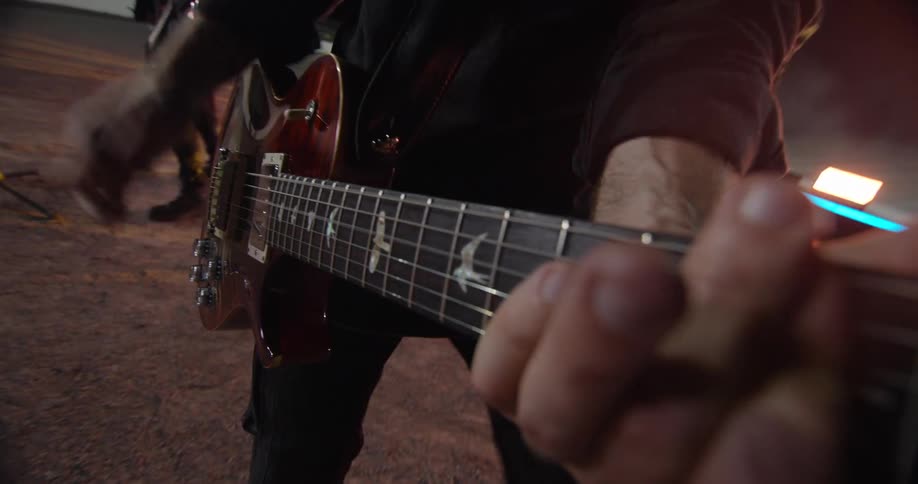 The men are playing guitar together