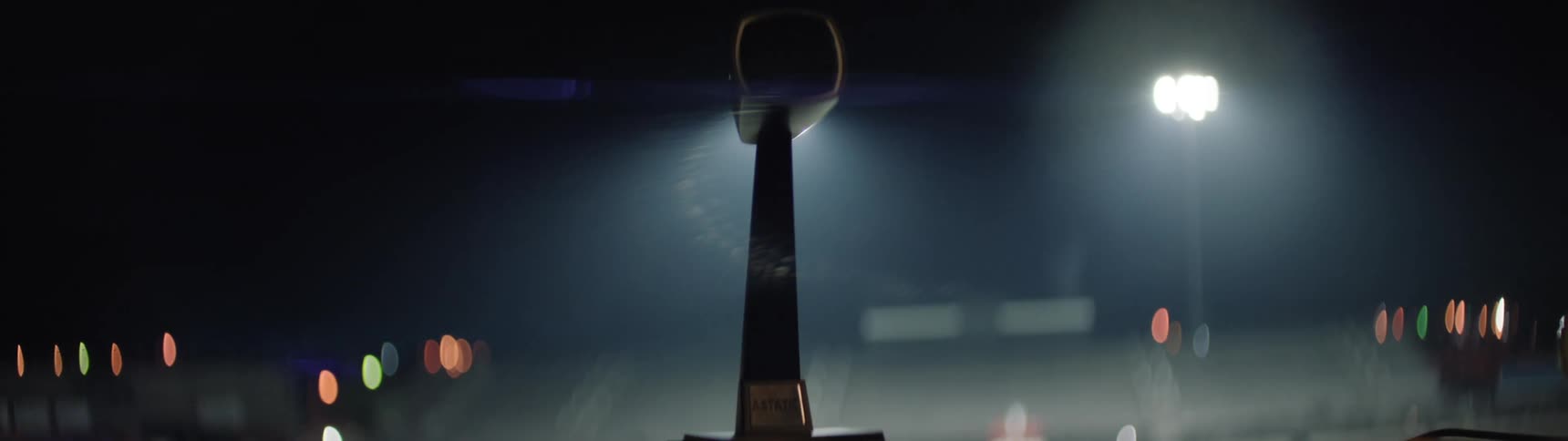 Person raises mic in the air under bright stadium lights