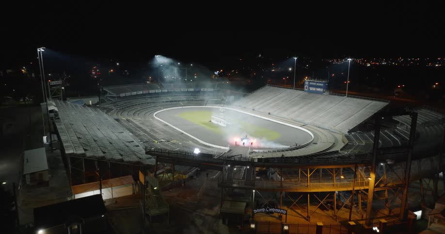 A stadium with an open roof glows under bright lights at night