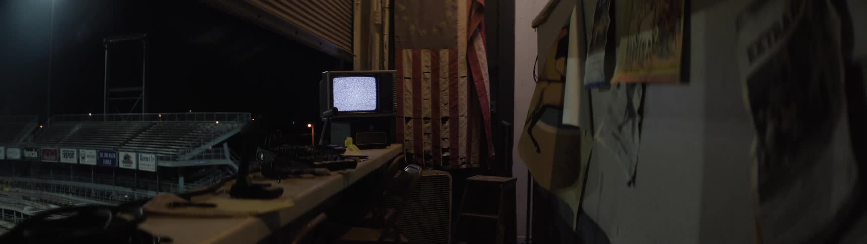 A monitor running in an empty broadcasting room at the football stadium at night