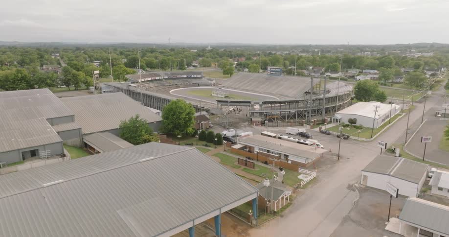 Aerial view of a racetrack surrounded by metal structures and parked vehicles