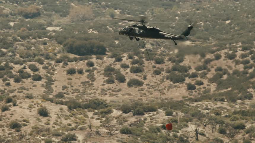 A helicopter flying while carrying a red basket