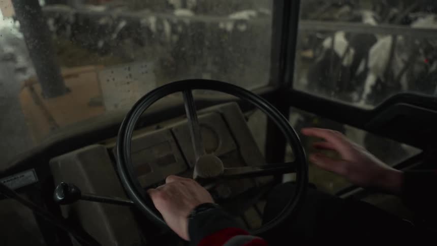 Hands operating the steering wheel of a farm tractor