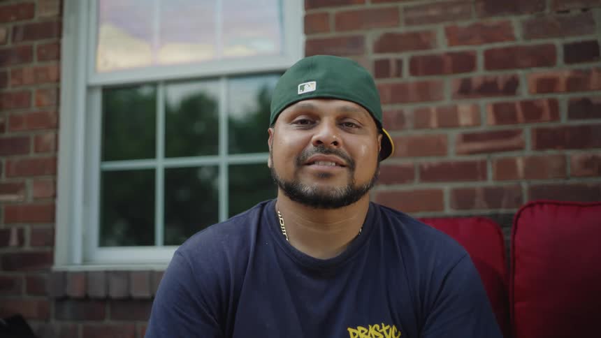 Man sits near the window in the brick wall and smiles