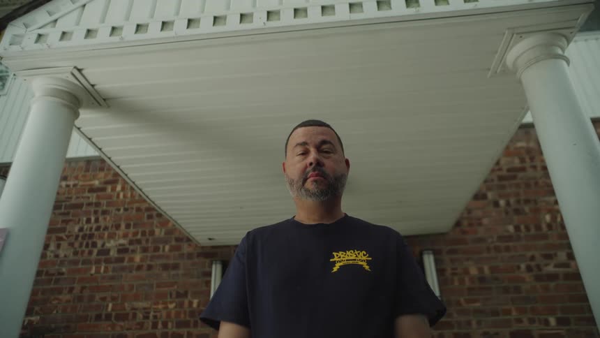 A middleaged man stands on his front porch his expression heavy with sadness