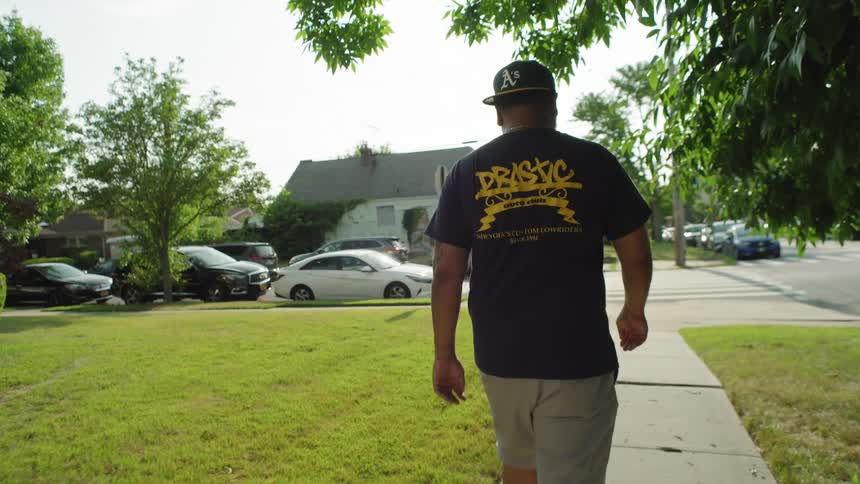 Man walking on a suburban sidewalk with parked cars on a sunny day
