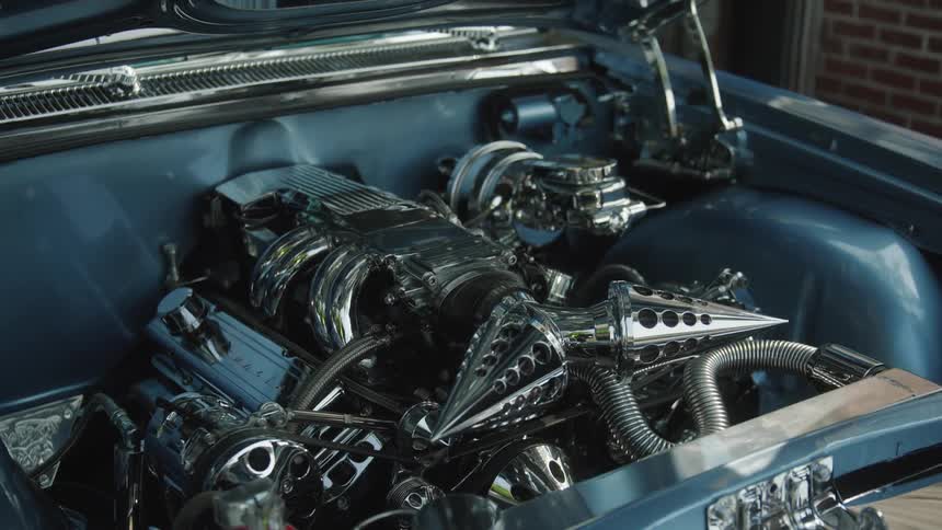 A blue car with a brandnew shining engine sits inside a garage