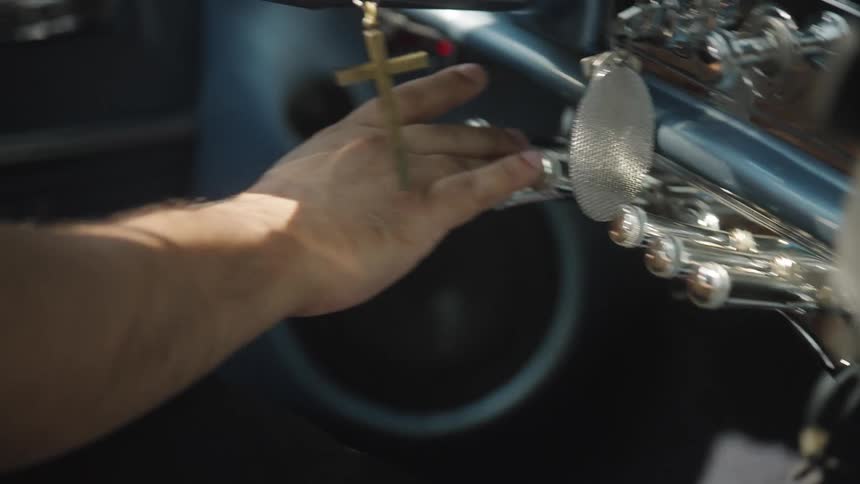 The man presses the knobs on the car dashboard