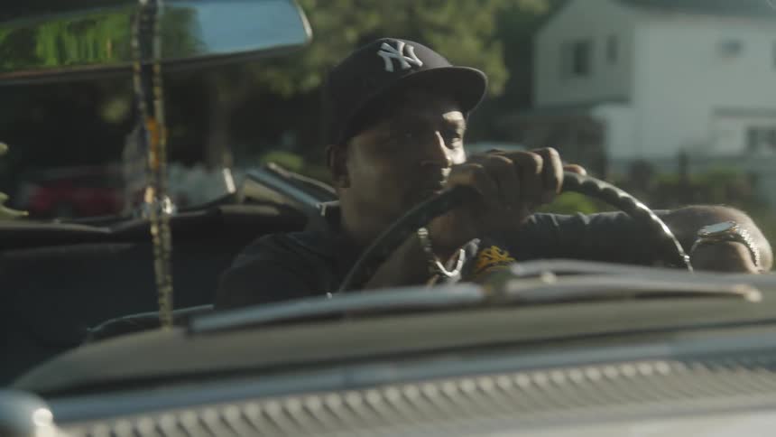 A black man driving a convertible car