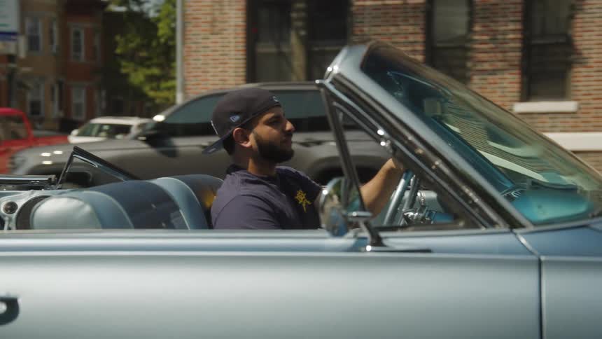 A man wearing a hat driving a car
