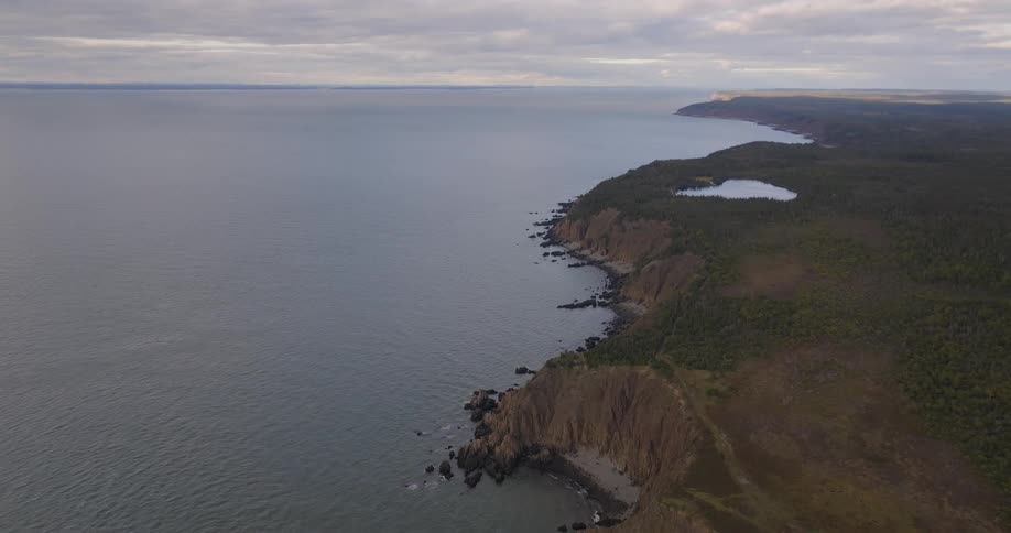 Aerial view of a coastal cliff with green slopes under a clear sky