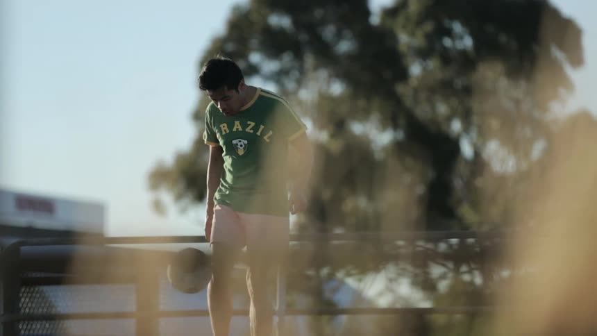 Man kicking a soccer ball around in the sun