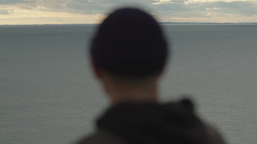 Person gazing at the sea under a cloudy sky