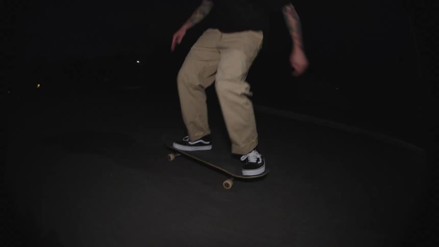 A man skateboarding on the street at night performing tricks
