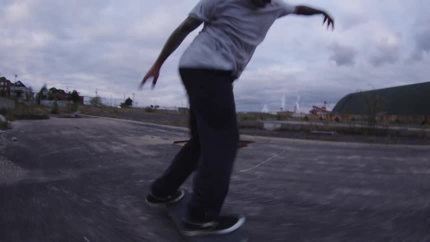 Person wearing a yellow cap falling during a skate trick on an outdoor track